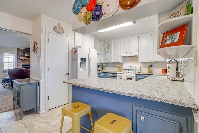 kitchen with a fireplace, white cabinetry, a peninsula, white appliances, and under cabinet range hood