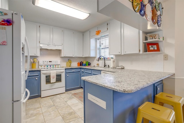 kitchen featuring a sink, a peninsula, blue cabinets, white appliances, and under cabinet range hood