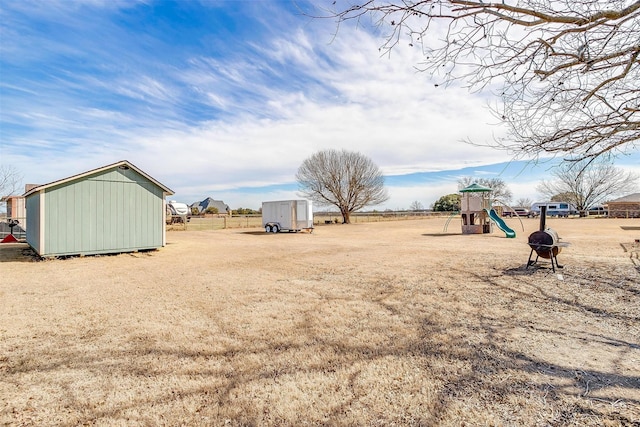 view of yard with a storage unit, playground community, and an outbuilding