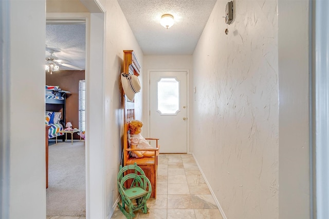 entryway featuring a textured ceiling, a textured wall, and baseboards