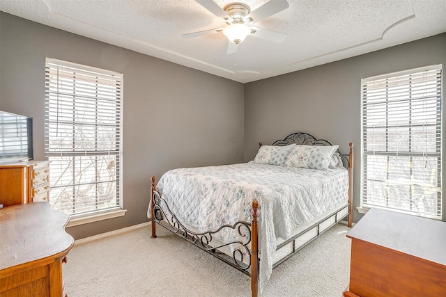 bedroom with light carpet, ceiling fan, baseboards, and a textured ceiling