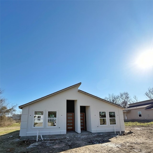 rear view of property with an outdoor structure and stucco siding