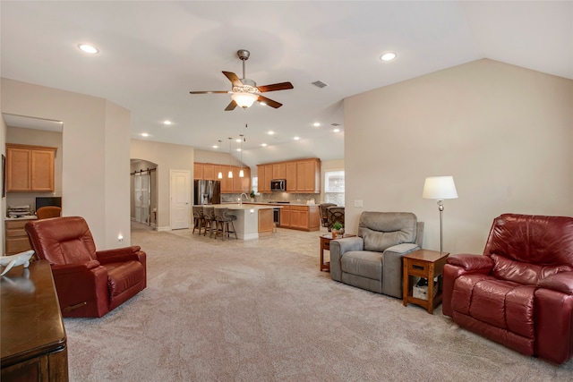 living area with lofted ceiling, light carpet, visible vents, and a ceiling fan