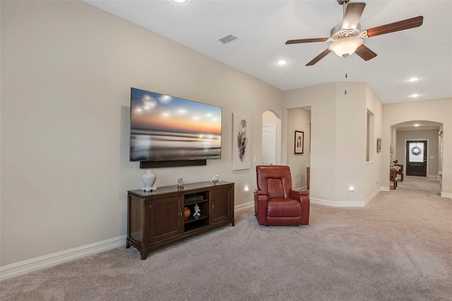 living area with arched walkways, baseboards, visible vents, and light colored carpet