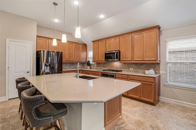 kitchen with a breakfast bar area, a sink, appliances with stainless steel finishes, backsplash, and an island with sink