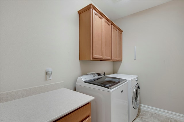 clothes washing area with washing machine and dryer, cabinet space, and baseboards