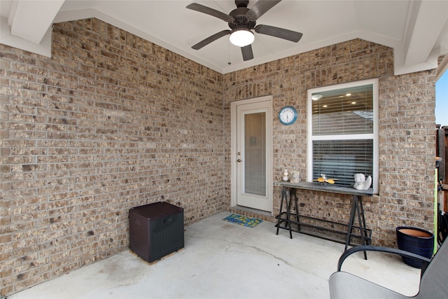 view of exterior entry with a patio, brick siding, and a ceiling fan