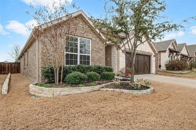 ranch-style home featuring brick siding, driveway, an attached garage, and fence