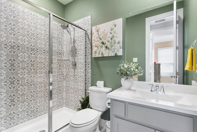 full bathroom with toilet, a stall shower, a textured wall, and vanity