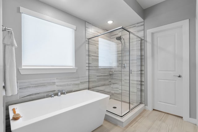 bathroom featuring a stall shower and a soaking tub