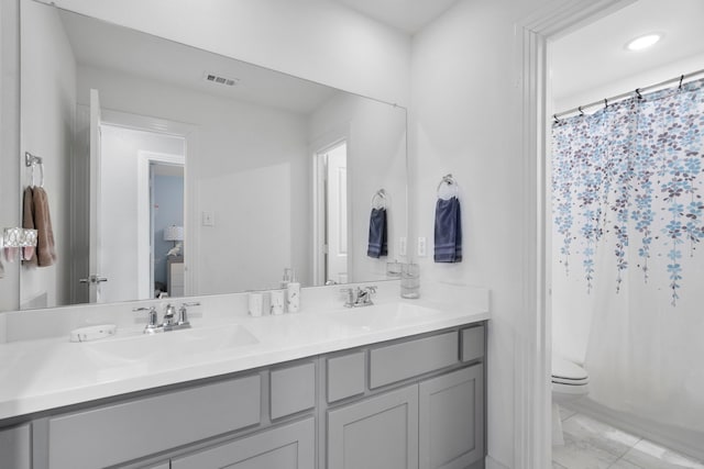 bathroom featuring double vanity, visible vents, toilet, and a sink