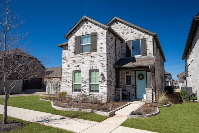 view of front of house with a front yard, concrete driveway, and brick siding