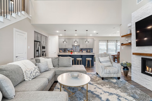 living room with a high ceiling, a fireplace, dark wood finished floors, and recessed lighting