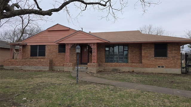 bungalow with a front yard, brick siding, and roof with shingles