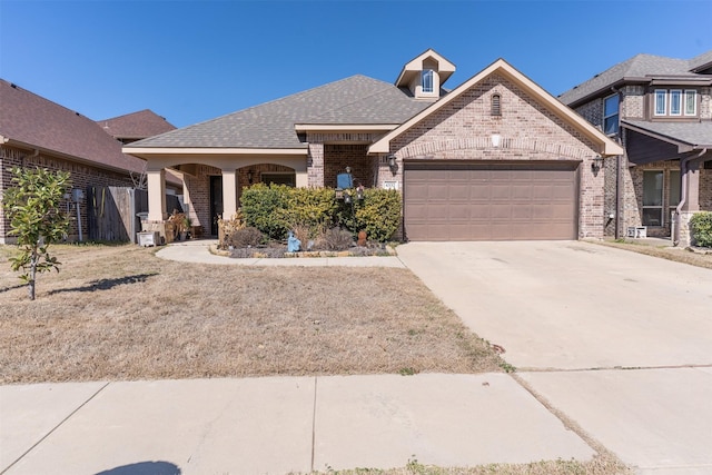 view of front facade featuring concrete driveway, brick siding, an attached garage, and roof with shingles