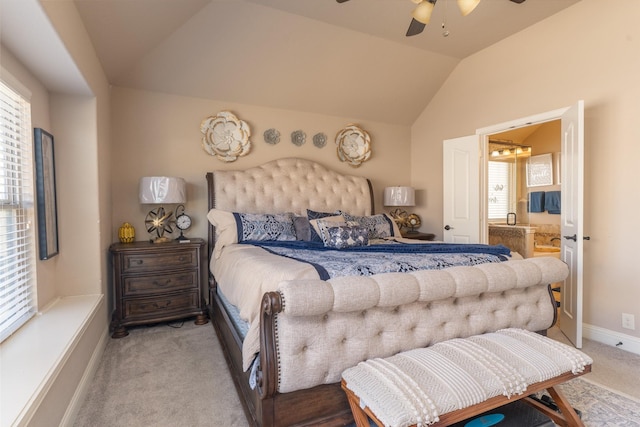 bedroom featuring a ceiling fan, light carpet, vaulted ceiling, ensuite bath, and baseboards