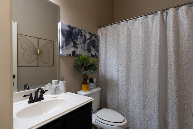 bathroom featuring toilet, vanity, and a textured wall