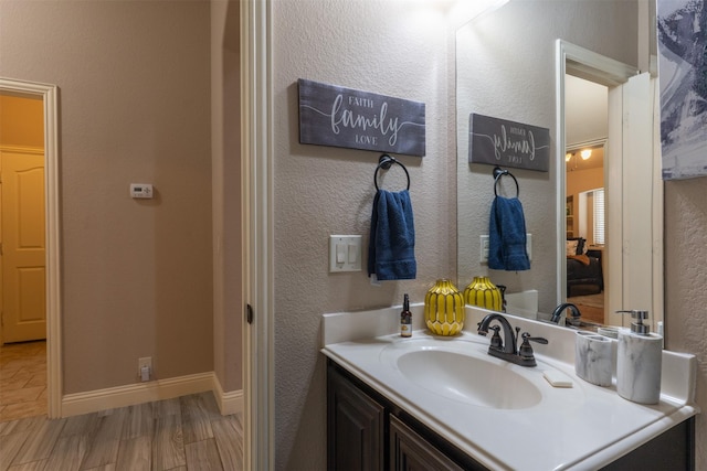 bathroom featuring a textured wall, wood finished floors, vanity, and baseboards