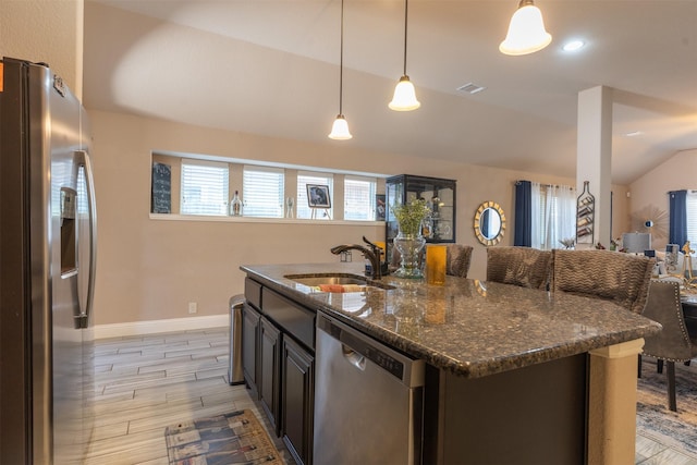 kitchen featuring visible vents, dark stone counters, vaulted ceiling, stainless steel appliances, and a sink