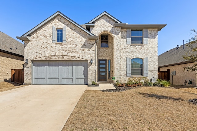 french country home with an attached garage, fence, concrete driveway, and brick siding