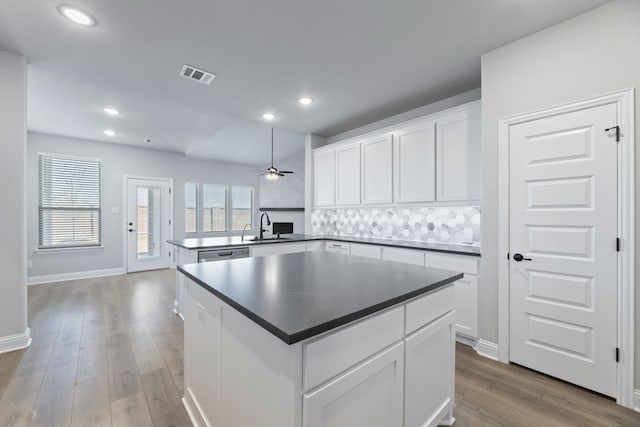 kitchen featuring a peninsula, a sink, wood finished floors, visible vents, and dishwasher