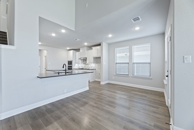 kitchen with white cabinets, visible vents, stainless steel microwave, and wood finished floors