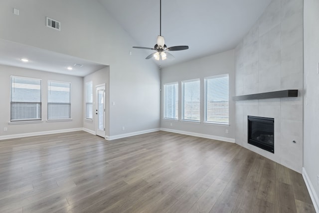 unfurnished living room with wood finished floors, a tile fireplace, visible vents, and a healthy amount of sunlight