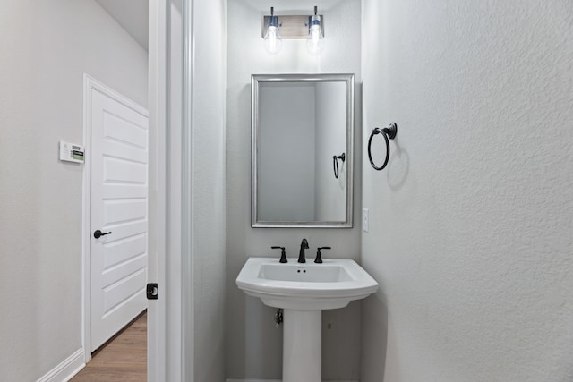 bathroom featuring a sink, wood finished floors, and a textured wall