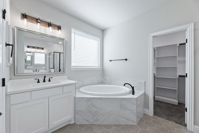 full bathroom featuring a garden tub, a spacious closet, a shower stall, vanity, and tile patterned flooring