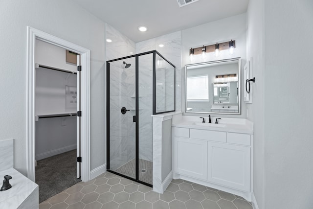 bathroom featuring visible vents, a spacious closet, a stall shower, vanity, and baseboards