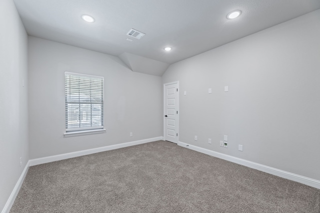 spare room featuring lofted ceiling, recessed lighting, carpet flooring, visible vents, and baseboards