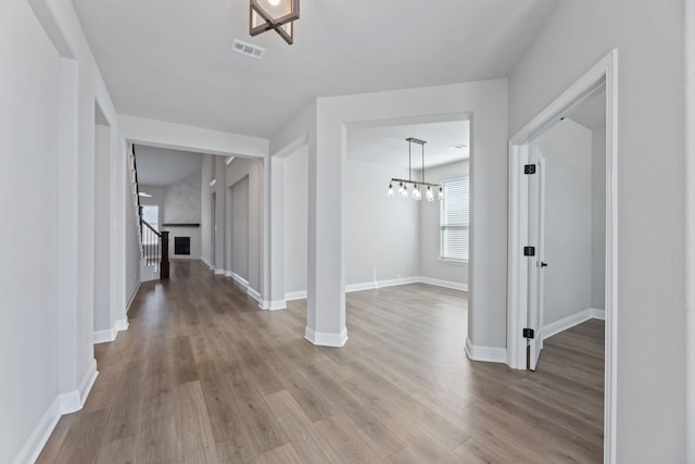 hall with stairway, wood finished floors, visible vents, and baseboards