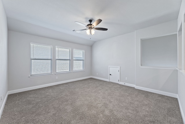 carpeted empty room featuring baseboards, vaulted ceiling, visible vents, and a ceiling fan