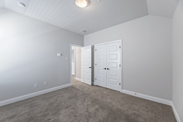 unfurnished bedroom with carpet floors, a closet, visible vents, vaulted ceiling, and baseboards