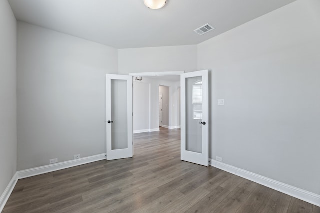 unfurnished room featuring french doors, visible vents, baseboards, and wood finished floors