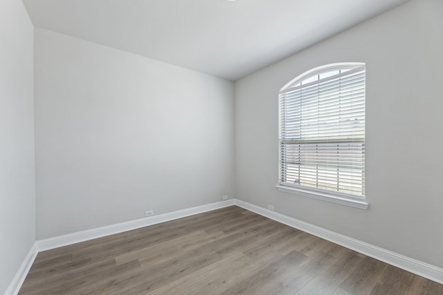 empty room featuring plenty of natural light, baseboards, and wood finished floors