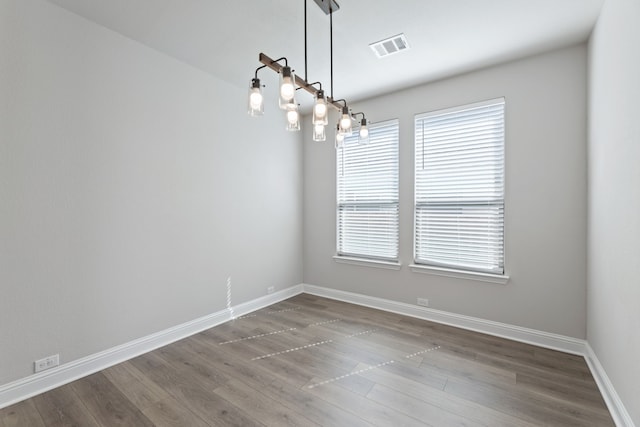 empty room featuring baseboards, visible vents, and dark wood-style flooring