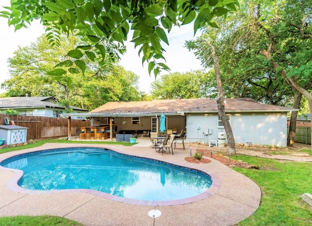 view of pool with a fenced backyard, a storage unit, a fenced in pool, a patio area, and an outbuilding