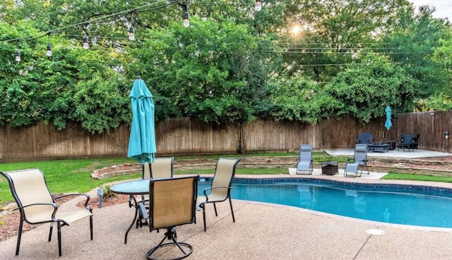 view of swimming pool with a fenced in pool, outdoor dining area, a patio area, a fenced backyard, and a fire pit