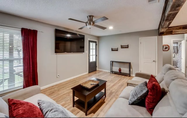 living room featuring baseboards, ceiling fan, a textured ceiling, and light wood-style floors