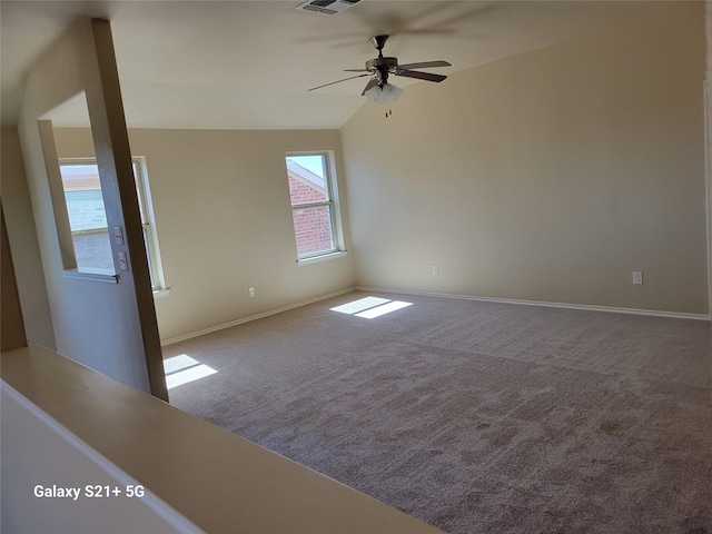 spare room featuring carpet flooring, visible vents, baseboards, vaulted ceiling, and a ceiling fan