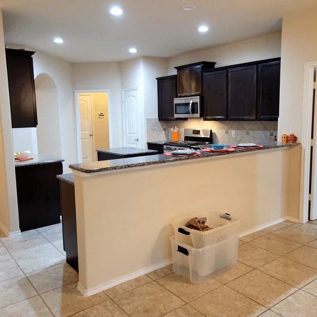 kitchen featuring stainless steel appliances, arched walkways, dark stone counters, and decorative backsplash