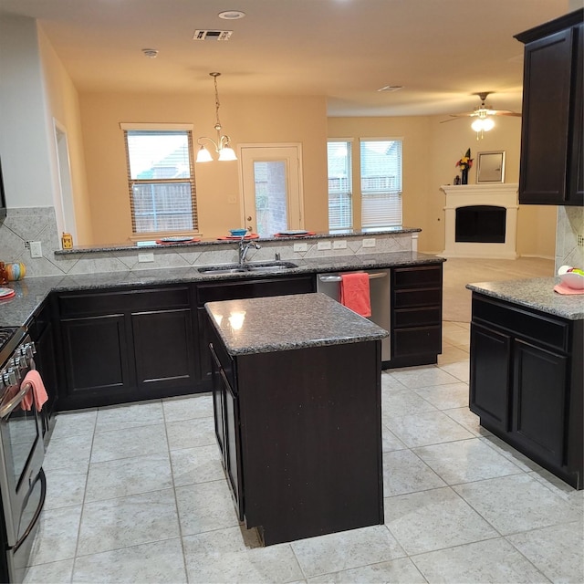 kitchen featuring visible vents, a sink, stainless steel appliances, a fireplace, and backsplash