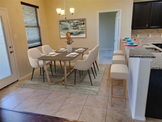 dining room with an inviting chandelier, baseboards, and light tile patterned flooring