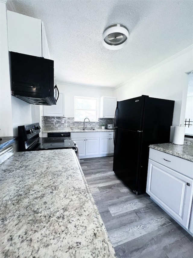 kitchen featuring a textured ceiling, a sink, white cabinets, black appliances, and light wood finished floors