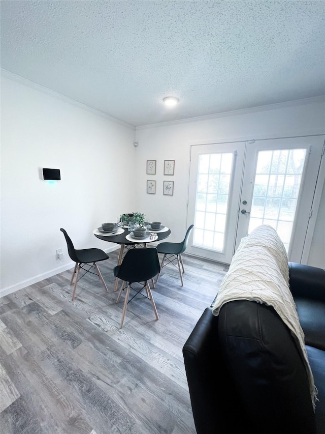 dining room featuring a textured ceiling, baseboards, wood finished floors, and crown molding