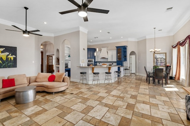 living room with stone tile floors, baseboards, and ceiling fan with notable chandelier