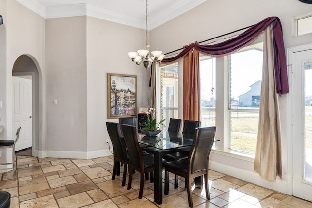 dining space with arched walkways, a notable chandelier, baseboards, ornamental molding, and stone tile flooring