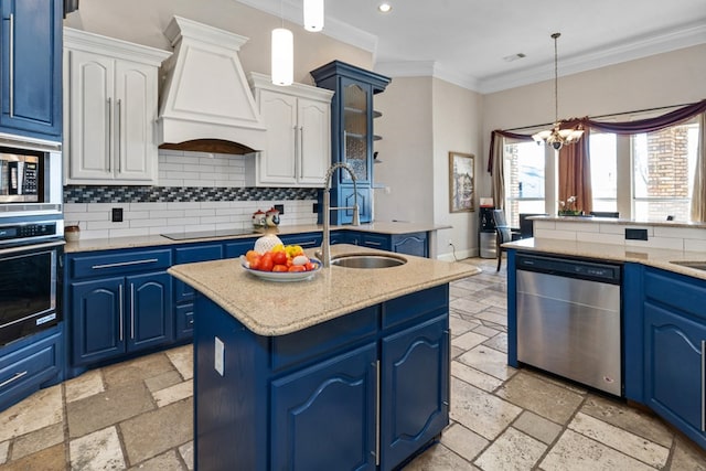 kitchen with blue cabinets, a sink, appliances with stainless steel finishes, custom exhaust hood, and stone tile flooring