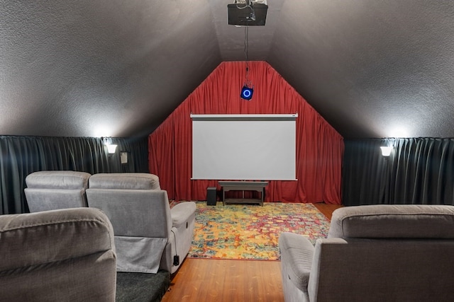 cinema featuring wood walls, a textured ceiling, vaulted ceiling, and wood finished floors